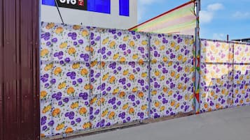 A building with a floral-patterned fence, a sign for 'OYO Hotel Japan Inn,' and a clear sky.