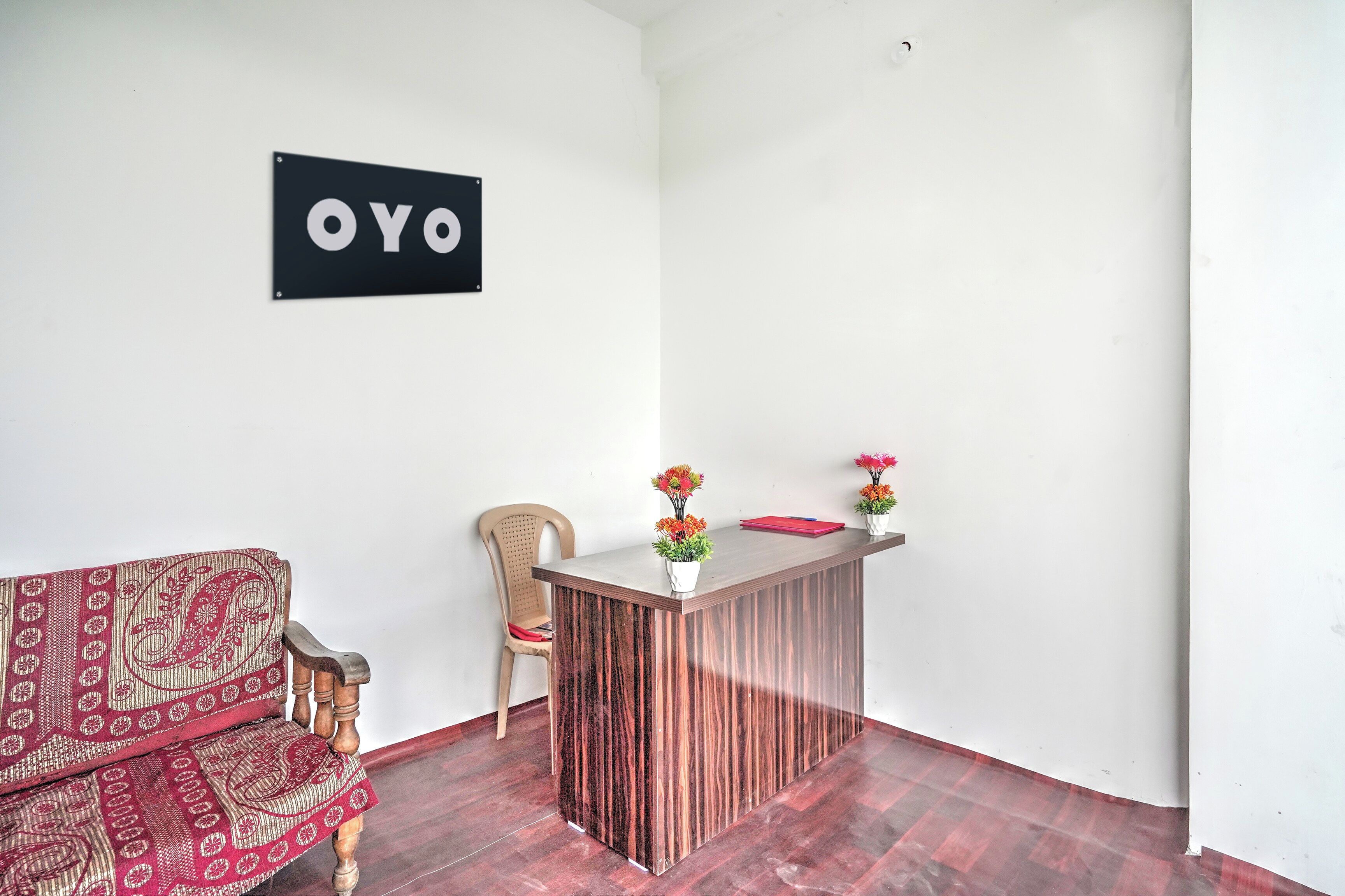 Ett receptionsområde med ett skrivbord i trä, en stol, en soffa och en skylt med texten ”OYO”.