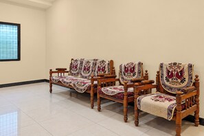 A room with a tiled floor and a window with a grid pattern. There are three wooden chairs with embroidered covers. - Hotel O New Royal Lodging And Boarding (Kamptee)