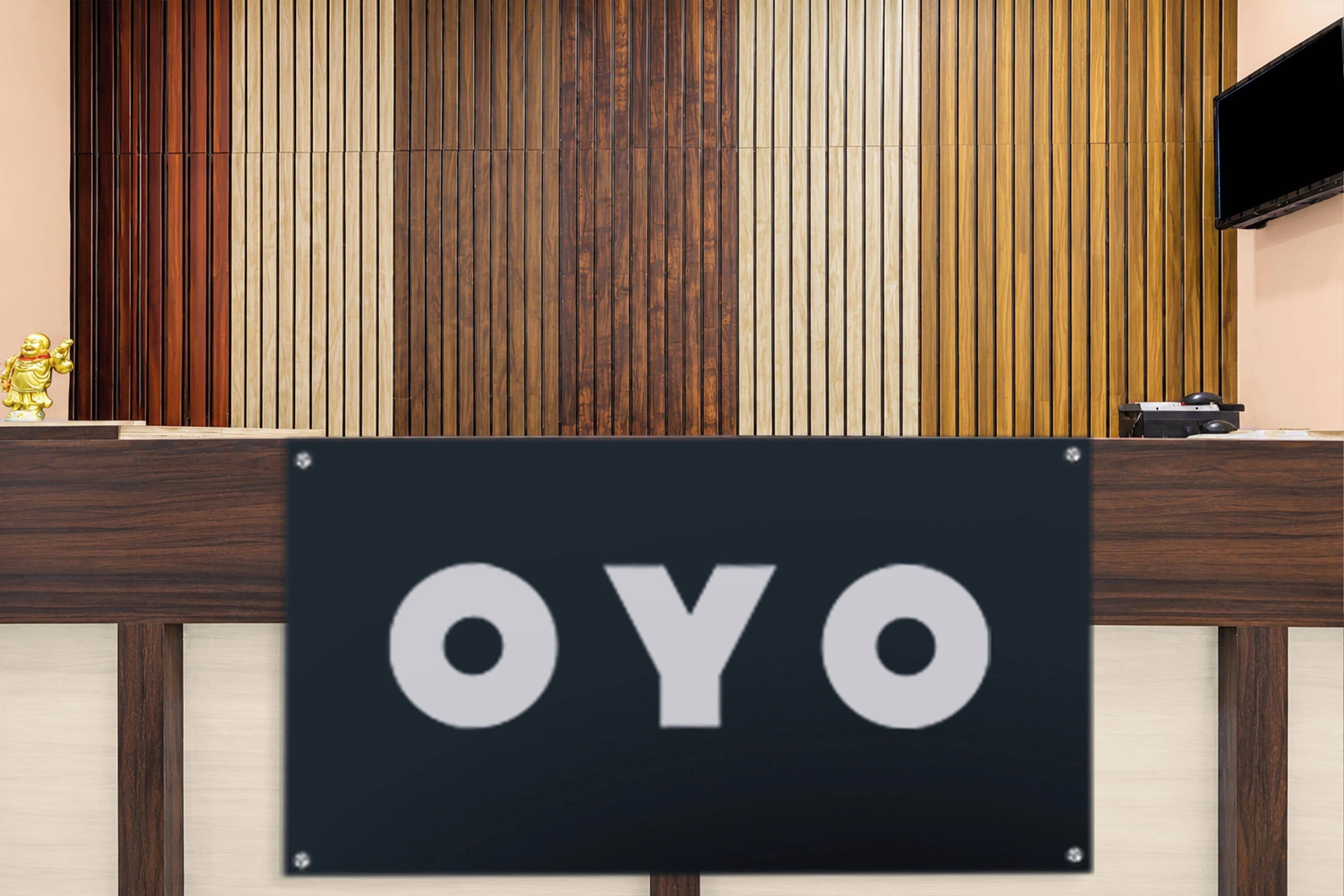 Balcão de recepção com placa indicando 'OYO' e uma figura dourada decorativa à esquerda.