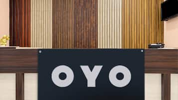 Balcão de recepção com placa indicando 'OYO' e uma figura dourada decorativa à esquerda.