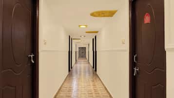 Un couloir d’hôtel avec des portes en bois, un sol à motifs et un éclairage encastré.