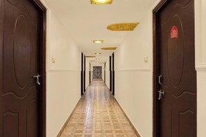 A hotel hallway with wooden doors, a patterned floor, and recessed lighting.
