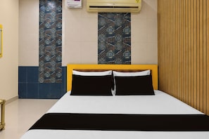 A hotel room with a bed, a wall-mounted air conditioner, and patterned tiles. - Hotel O New Royal Lodging And Boarding (Nagpur)