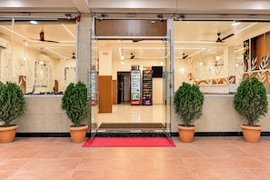 A hotel entrance with a red carpet, potted plants, and a vending machine. - Hotel O Veera Dine & Banquet (Kamptee)