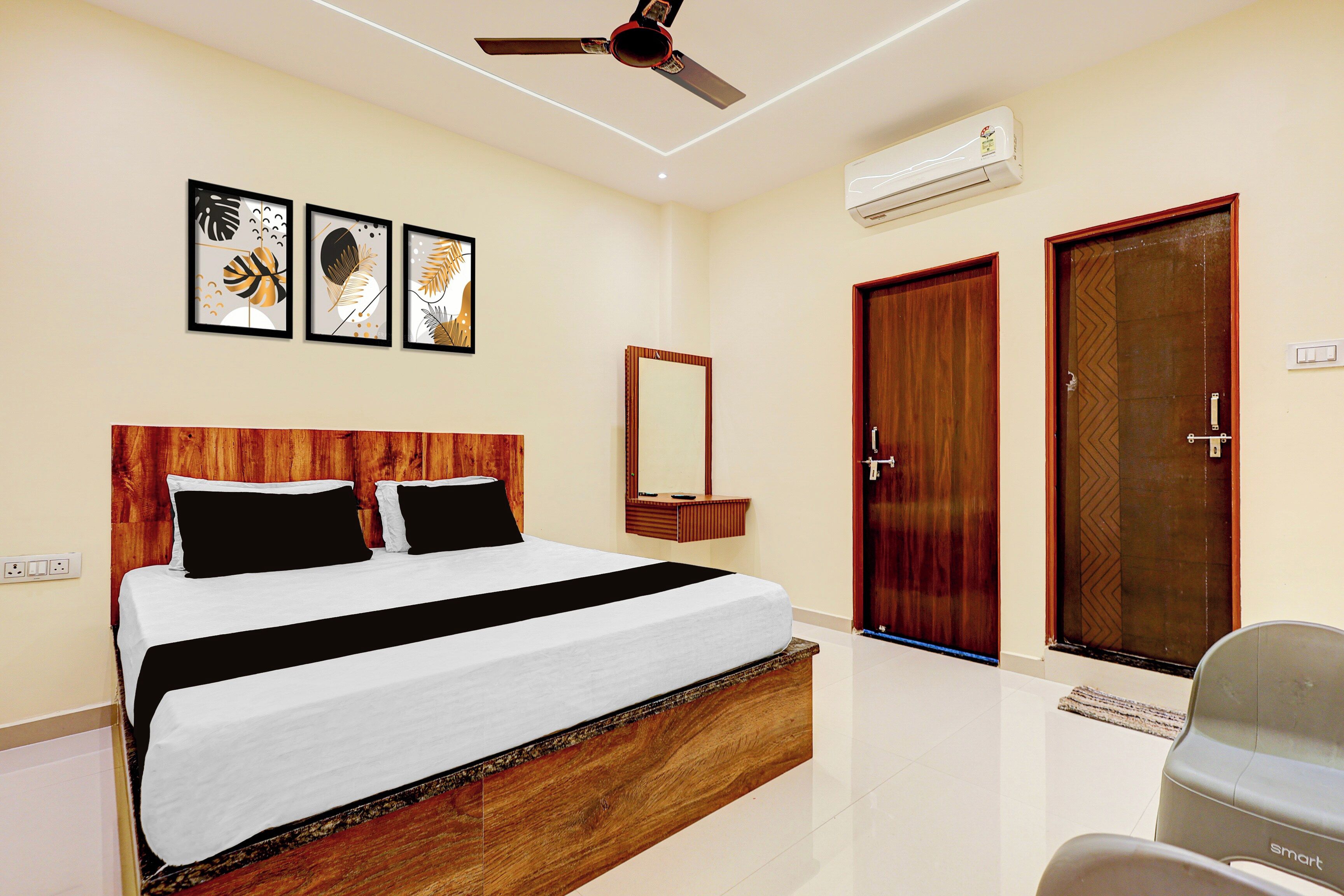 A hotel room with a bed, a ceiling fan, an air conditioner, a mirror, and two doors.