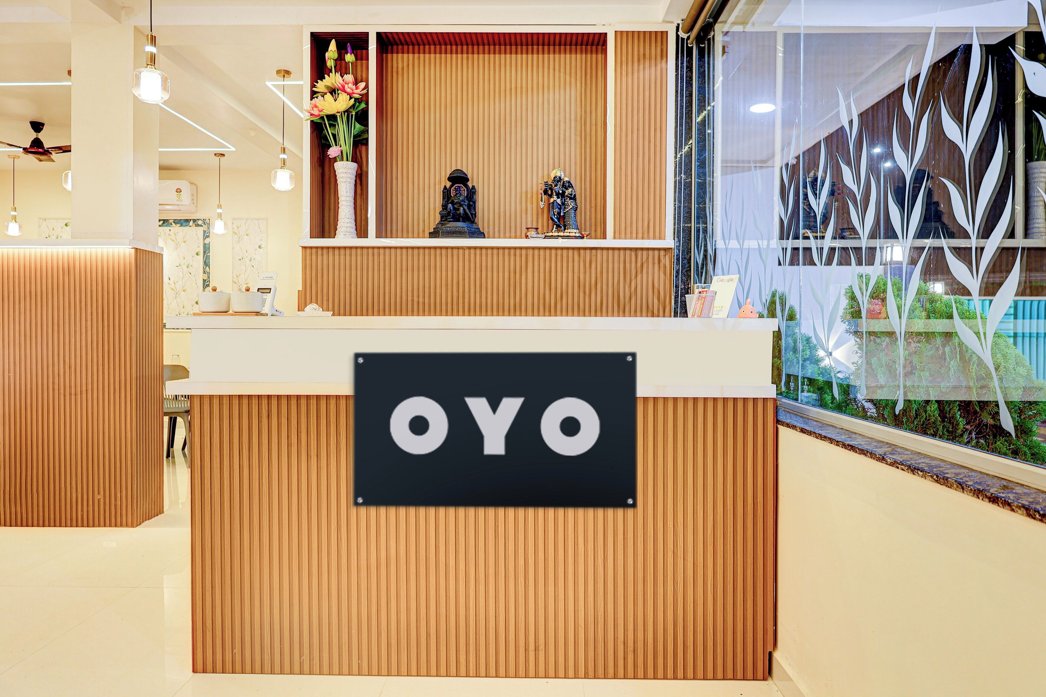 Un comptoir d’accueil avec une enseigne indiquant « OYO » et un vase décoratif rempli de fleurs.
