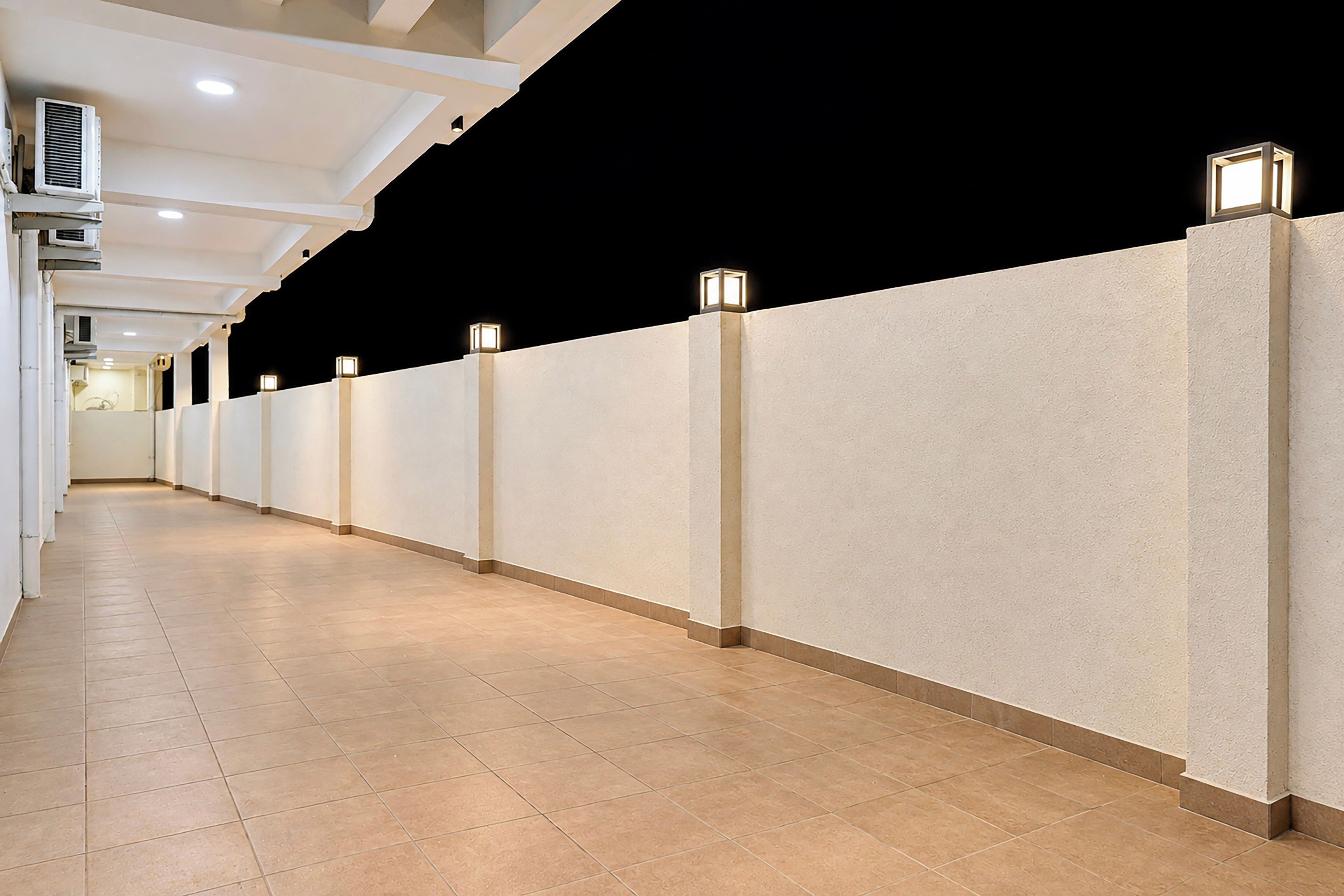 Un couloir doté d’un sol carrelé, de murs blancs et d’un éclairage encastré.