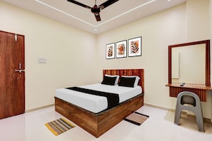 A bedroom with a wooden bed, a bedside table, a mirror, and a ceiling fan. - Hotel O Veera Dine & Banquet (Kamptee)
