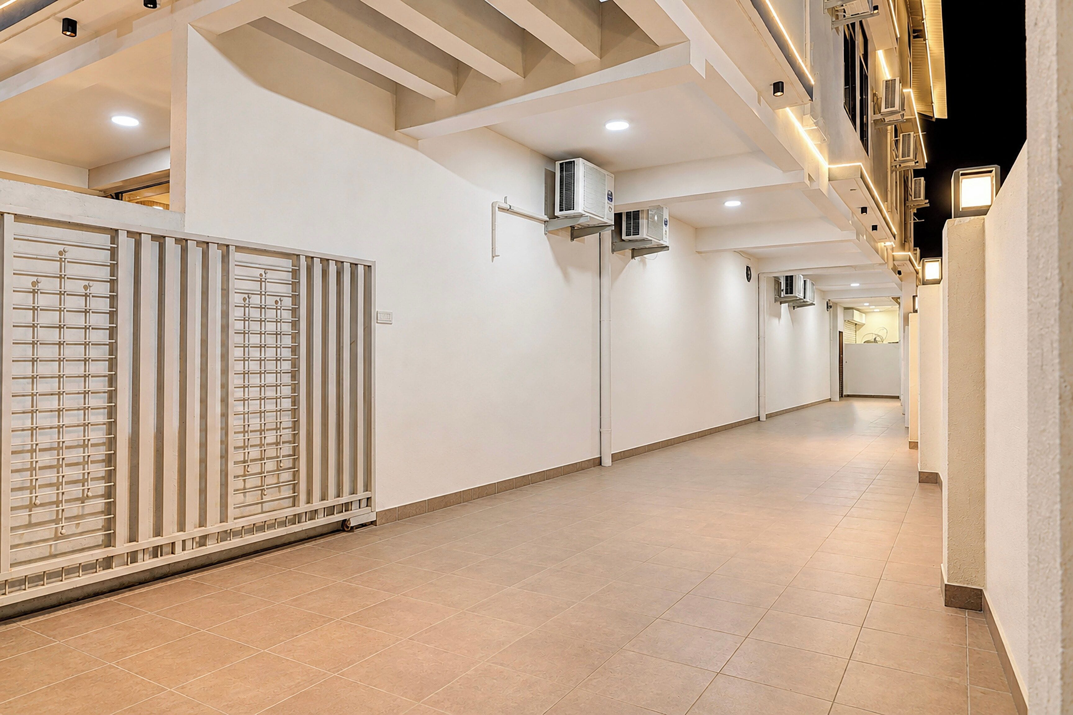 A corridor with white walls, tiled flooring, and air conditioning units mounted on the walls.