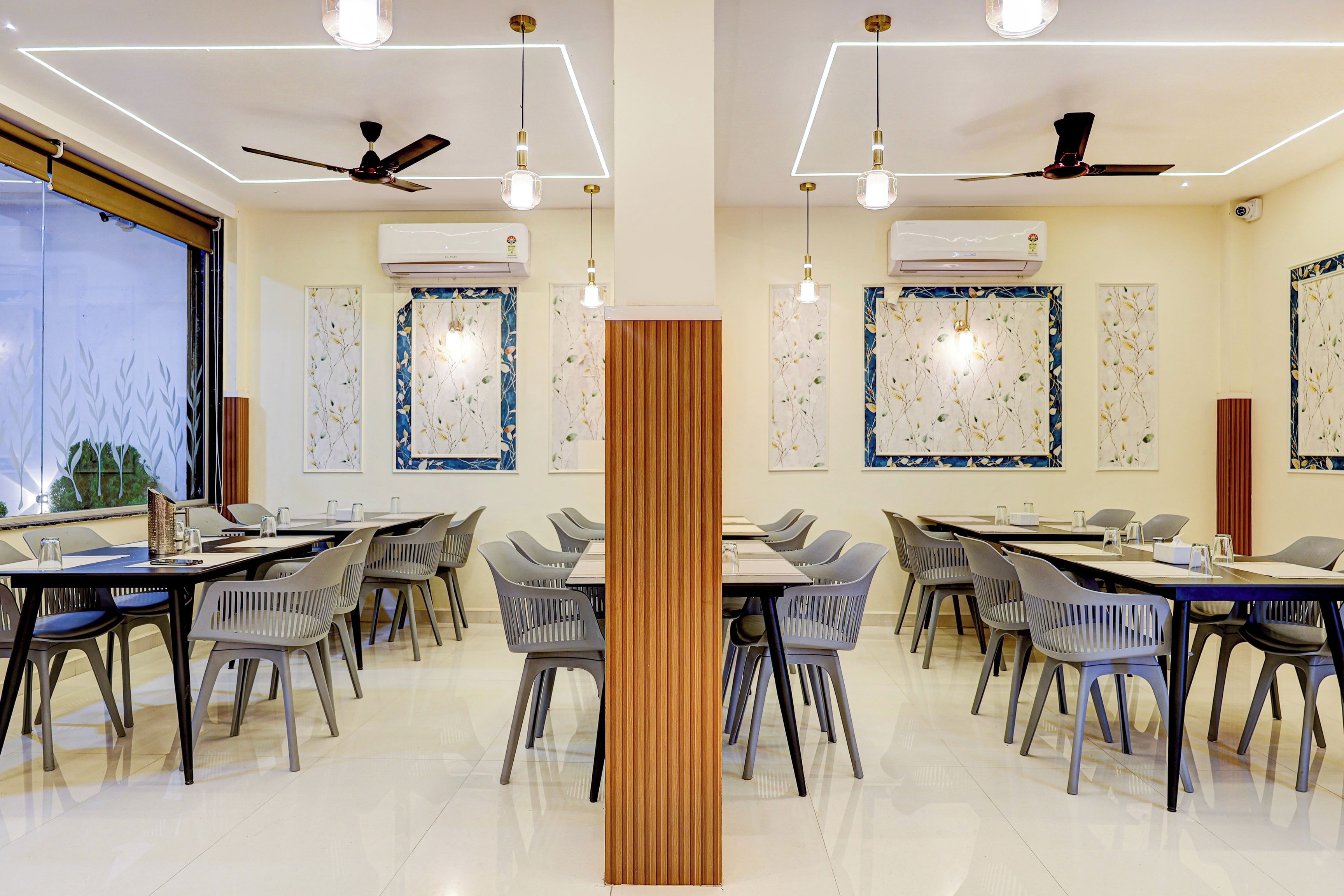 Sala de conferências com mesas, cadeiras, ventiladores de teto e ar-condicionado instalado nas paredes.