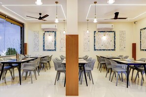 Sala de conferências com mesas, cadeiras, ventiladores de teto e ar-condicionado instalado nas paredes.