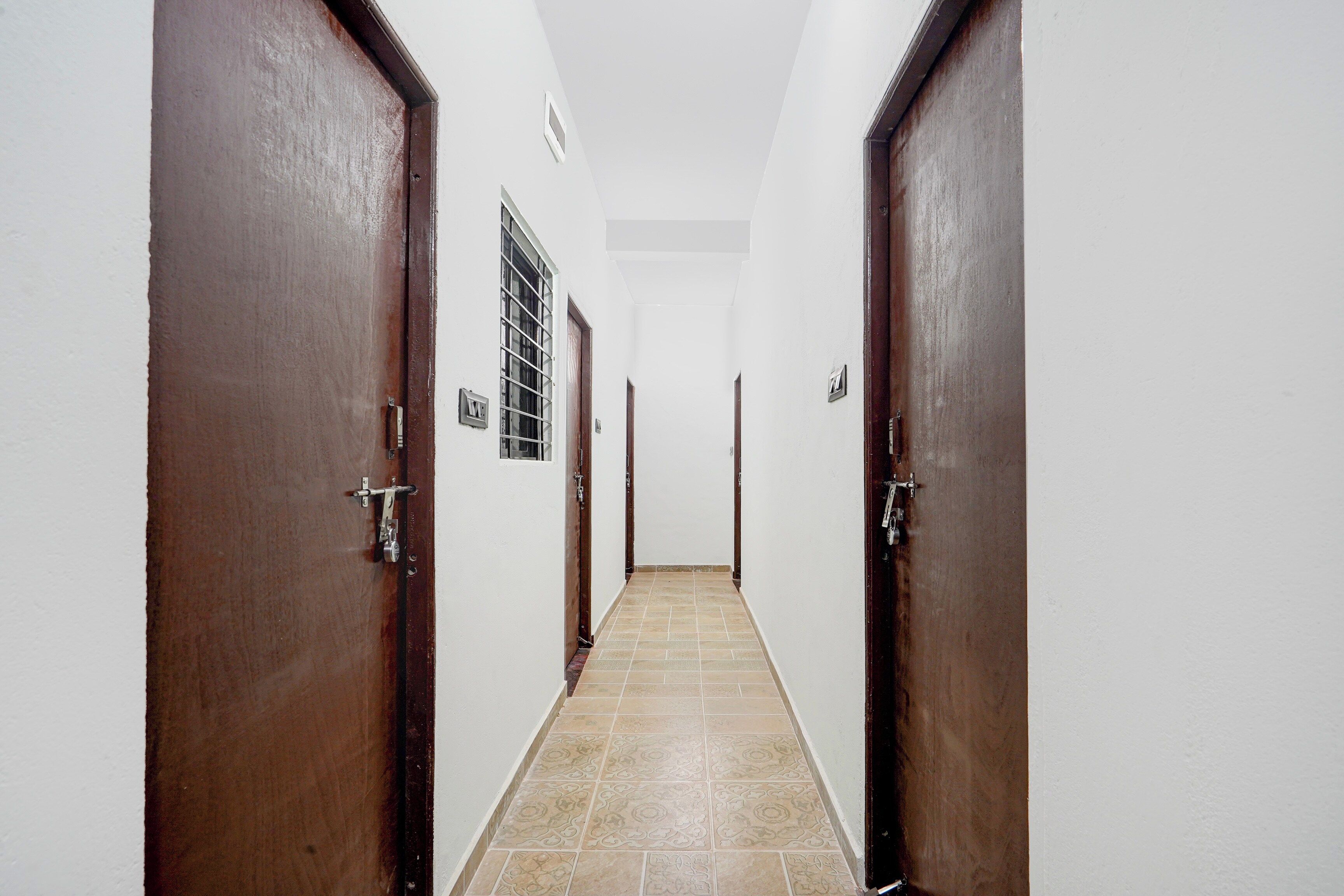 Un pasillo estrecho con puertas de madera y suelo de baldosas.