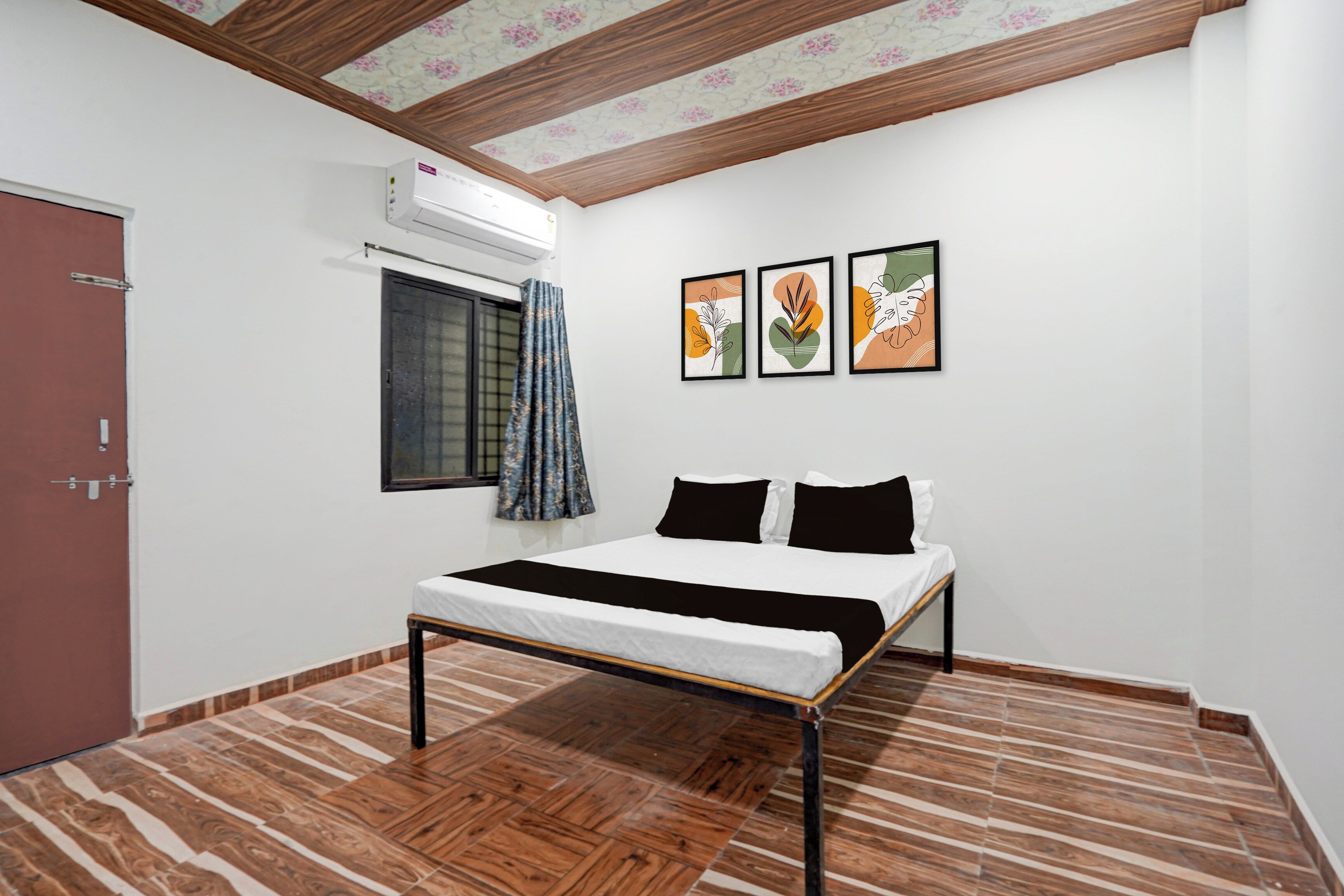 Un dormitorio con una cama, una ventana con cortinas y tres cuadros en la pared.