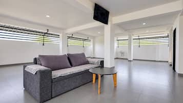 A modern interior with a grey sofa, a small round table, and a flat-screen TV mounted on the ceiling.