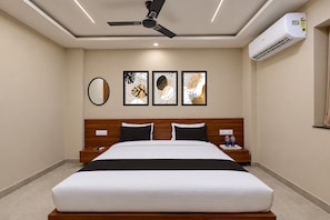 A hotel room with a bed, a nightstand, a mirror, and three framed artworks on the wall. - Hotel O SN HOTEL (Nagpur)