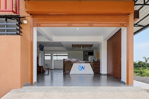A modern building entrance with a reception desk, a large window, and a view of greenery outside. - Hotel O SN HOTEL (Nagpur)