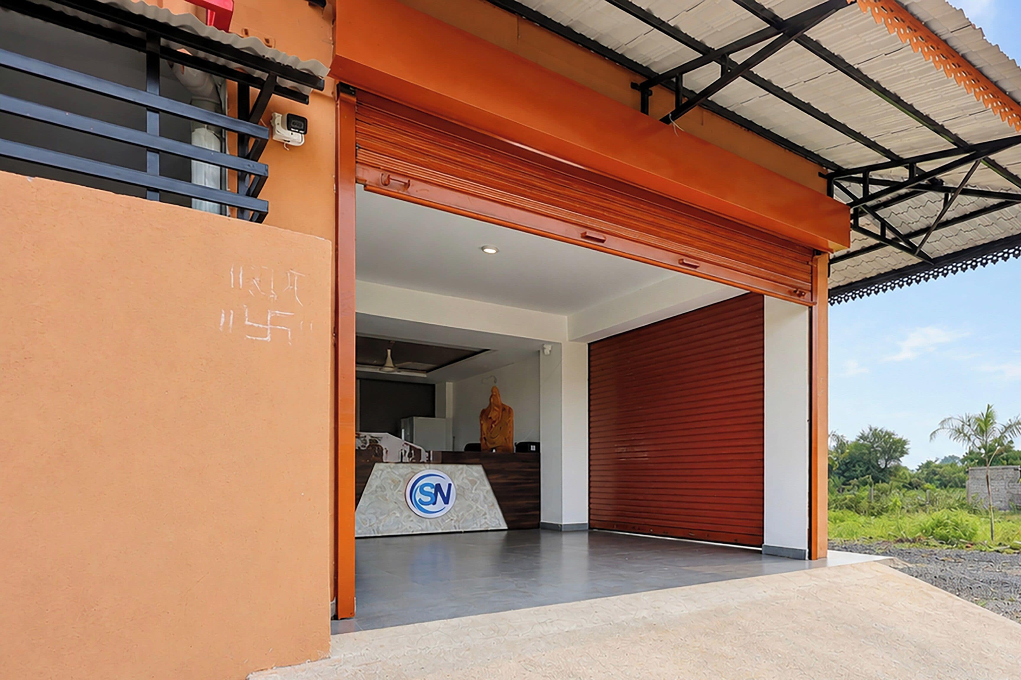 Um edifício moderno com porta de garagem, um logotipo na parede e céu azul ao fundo.