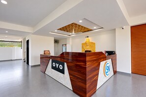 Un mostrador de recepción con un logotipo, un diseño geométrico en el techo y una estatua.