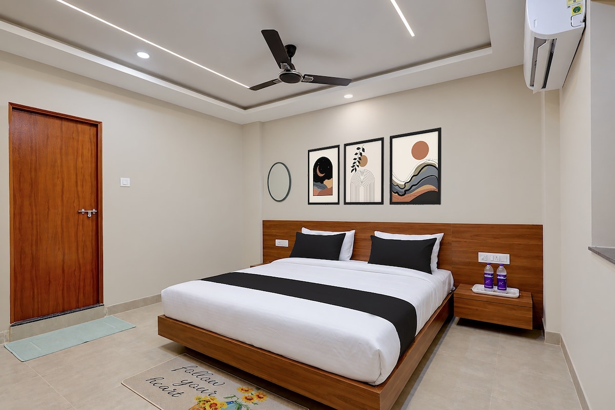 Una habitación de hotel con cama, mesita de noche, ventilador de techo, decoración en la pared y aire acondicionado.