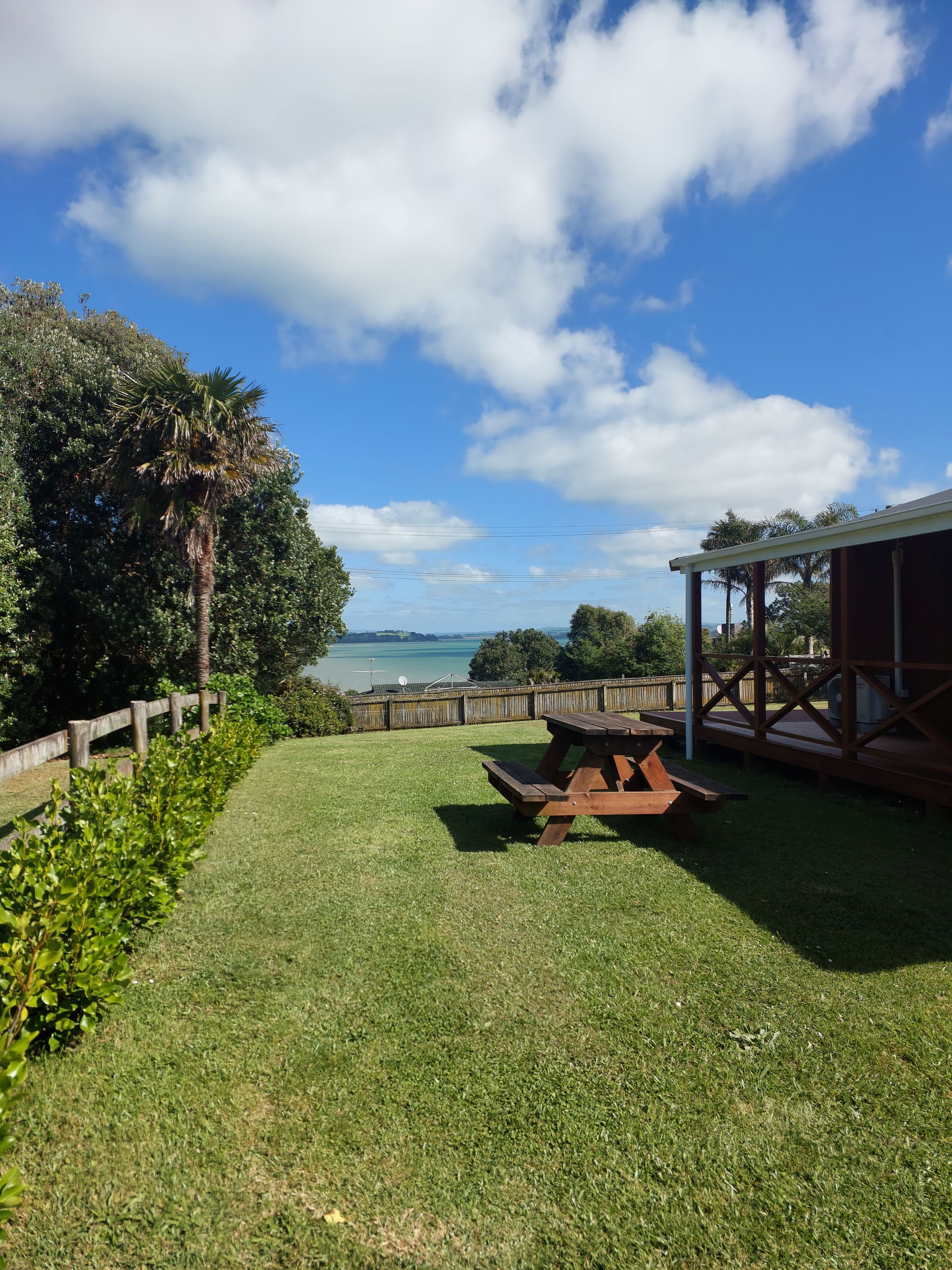 A grassy outdoor area with a picnic table and a wooden fence.