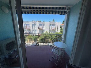 A balcony with a metal railing, a white table, and a chair. - New Listing (Canet-en-Roussillon)