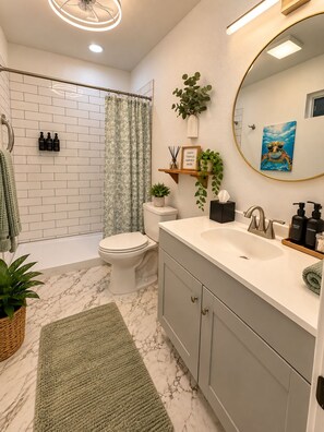 Ein modernes Badezimmer mit einer weißen Duschkabine, einer Toilette, einem Waschbecken mit Spiegel und einem grünen Teppich.