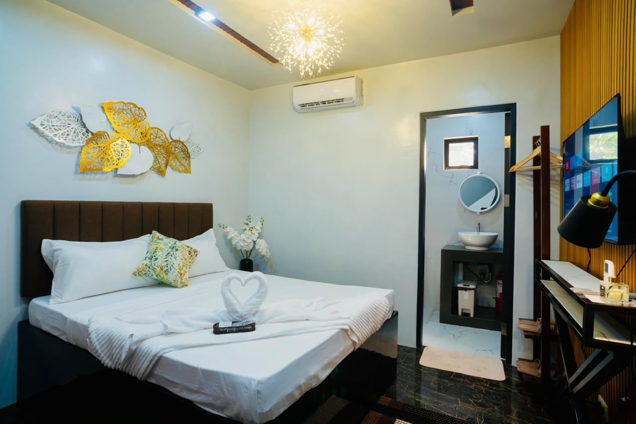 Une chambre d’hôtel comprenant un lit, une table de chevet, un bureau, une chaise, un miroir et un climatiseur fixé au mur.