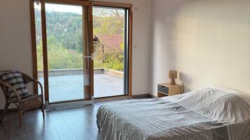 A bedroom with a bed, a chair, a nightstand, and a large sliding glass door leading to an outdoor area.