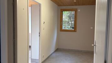 Ein Zimmer mit Holzboden, einem Fenster mit Blick auf Bäume und einem Fliesenboden.