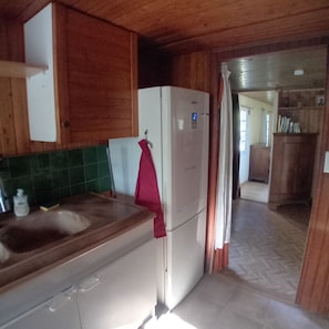 Una cocina con armarios de madera, un refrigerador blanco y una encimera con un lavabo.