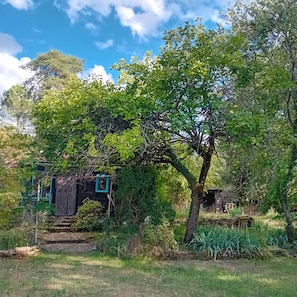 Un entorno rústico al aire libre con un árbol, una estructura de madera y un muro de piedra.