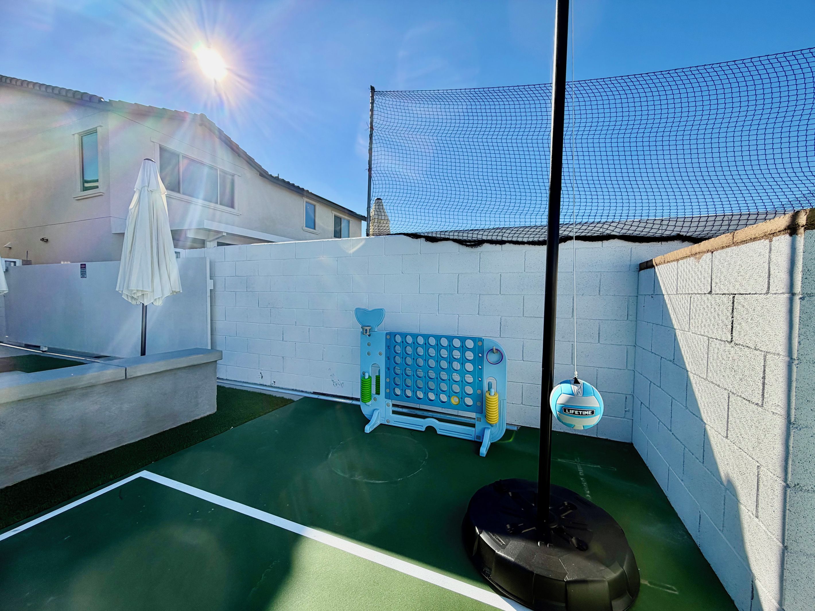 Un espace de jeux sur le toit, doté d’une surface verte, d’une structure de jeu bleue et d’une clôture blanche.