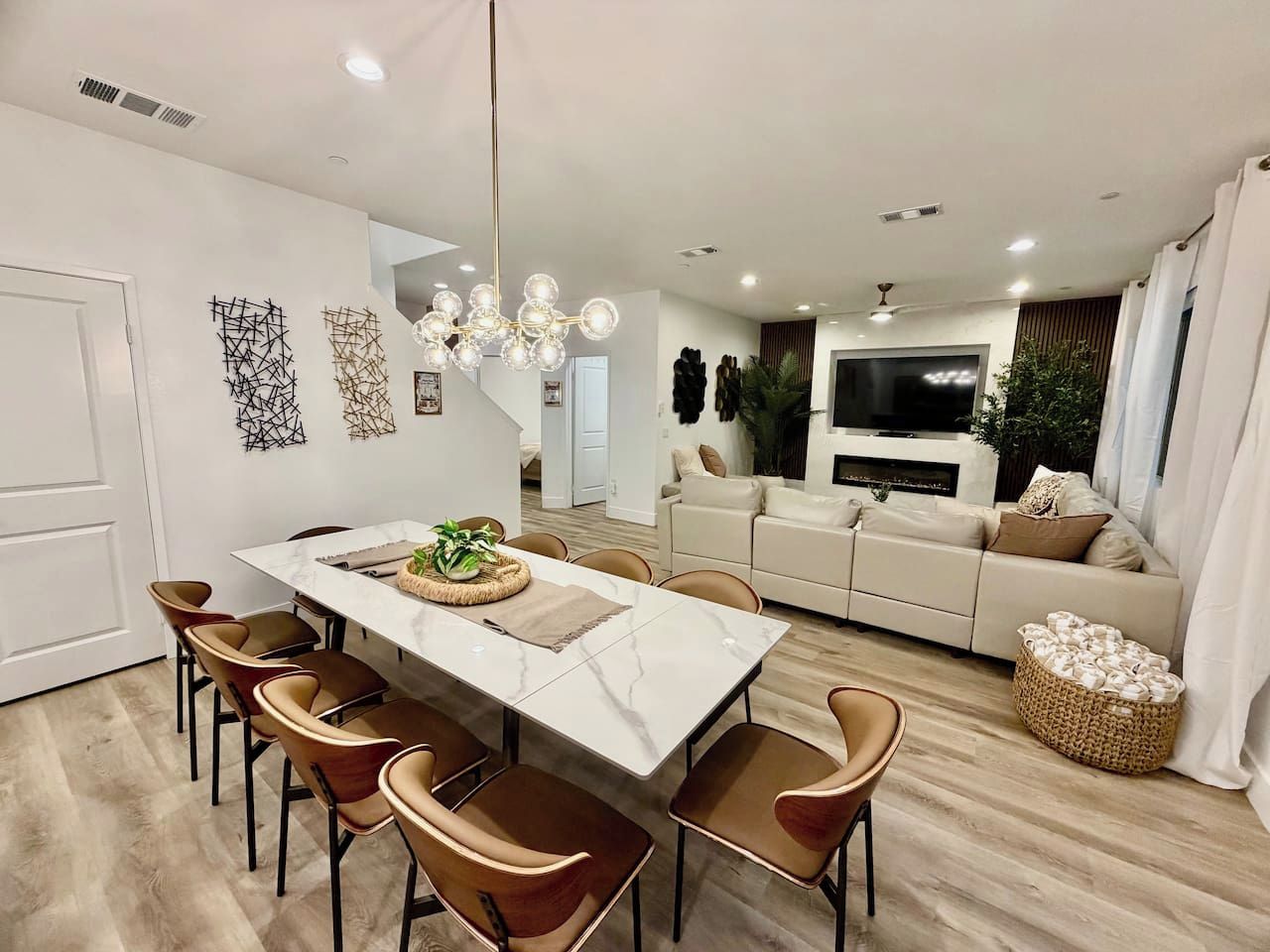 A modern living room with a sofa, TV, and a dining area with chairs and a table.