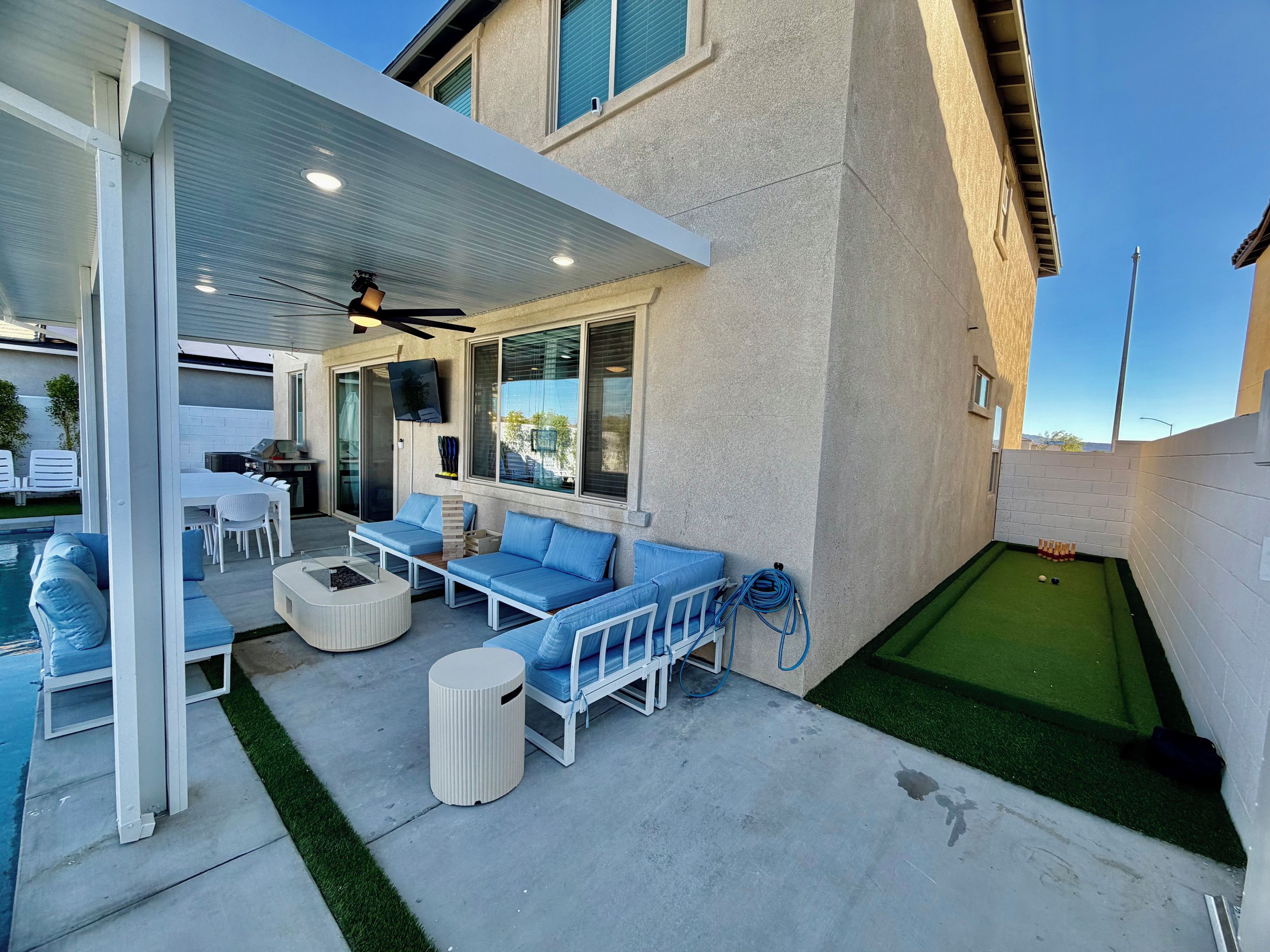 A covered patio area with outdoor seating, a pool, and a mini-golf setup.