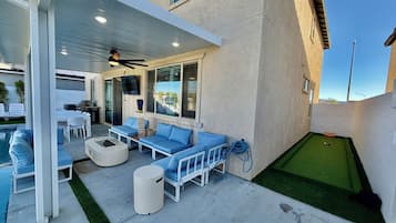 A covered patio area with outdoor seating, a pool, and a mini-golf setup.