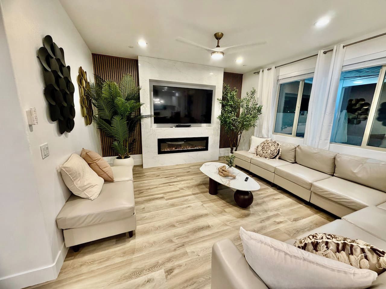 A modern living room with a flat-screen TV, a fireplace, a sofa set, and a coffee table.