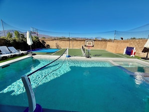En swimmingpool med basketballkurv og tennisnet.