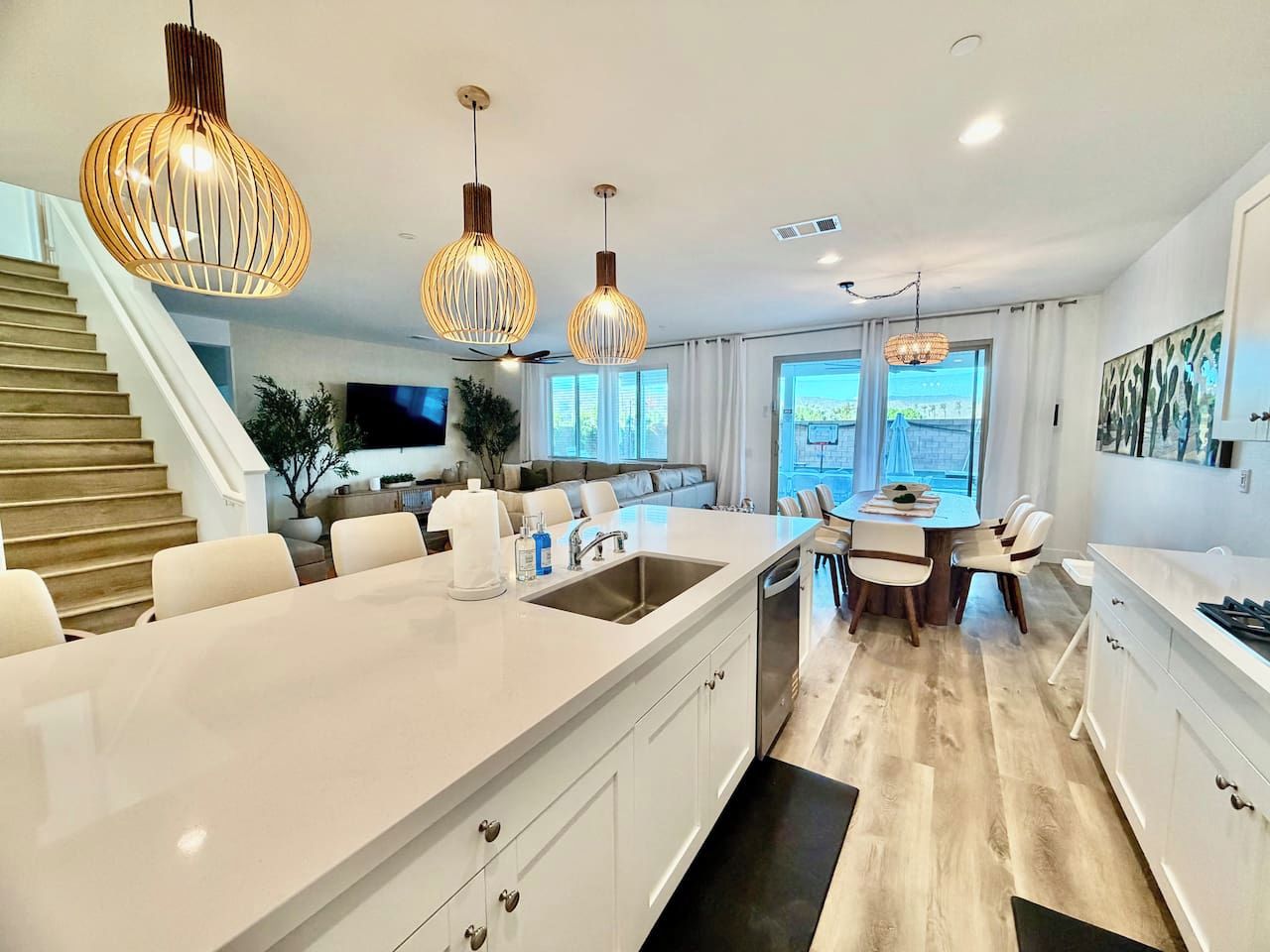 A modern kitchen with a central island, white cabinetry, and pendant lighting.