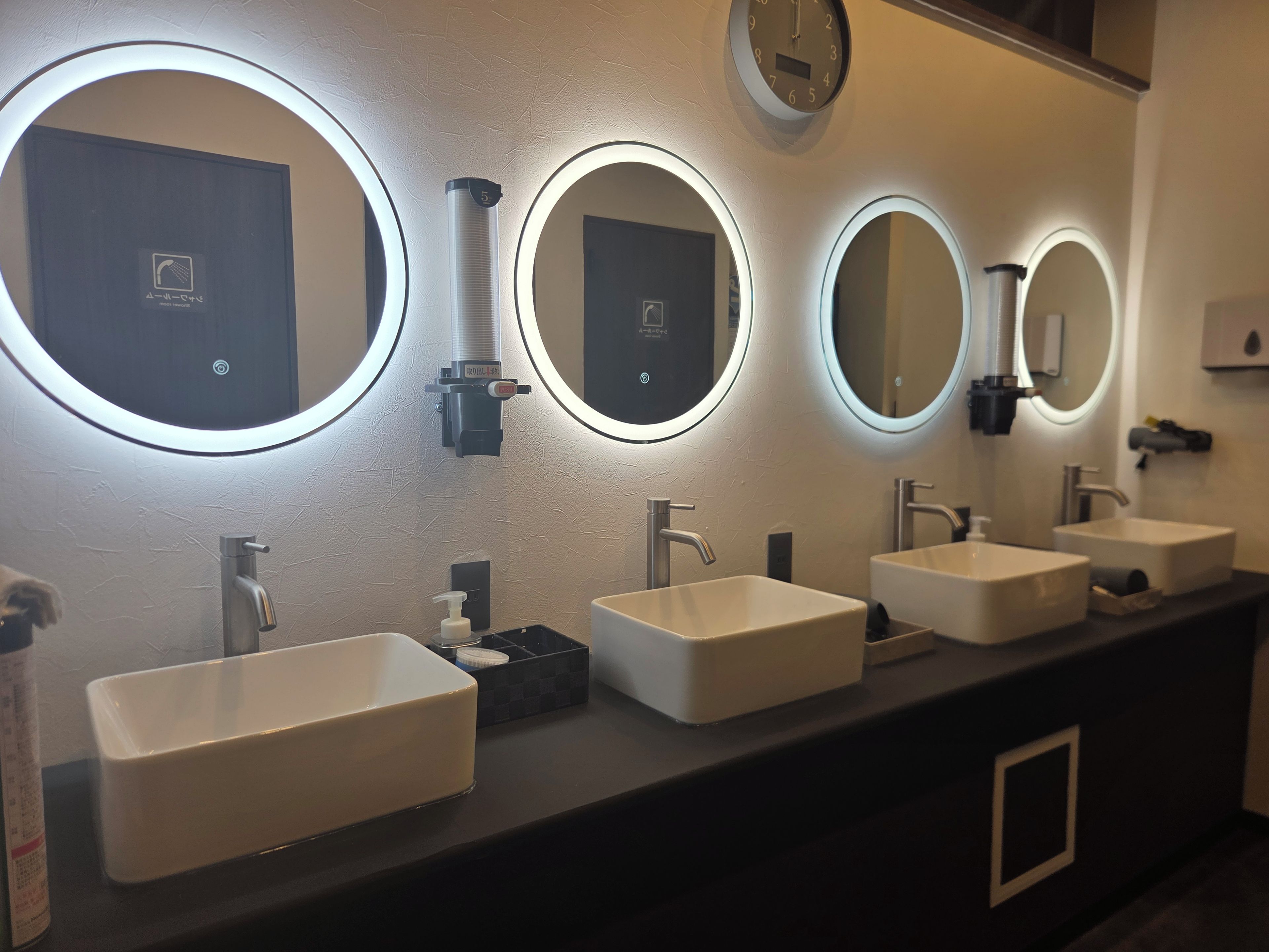 A modern bathroom with three sinks, each with a mirror above.
