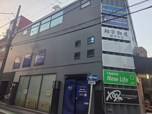 Un edificio con varios letreros, incluyendo un hotel Galaxy Pod, una tienda New Life y un gimnasio X Gym.