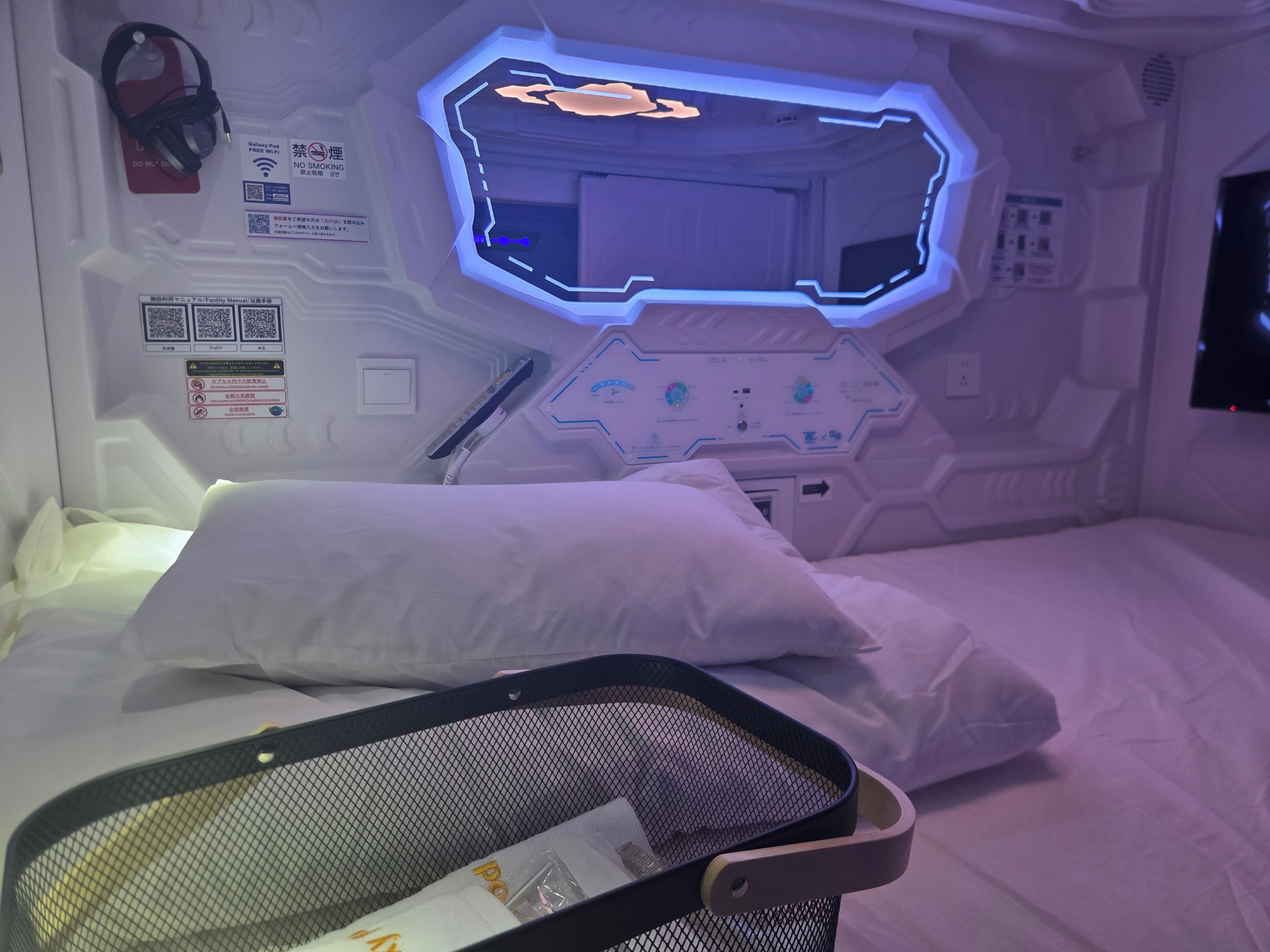 A futuristic room with a bed, a control panel, and a monitor.