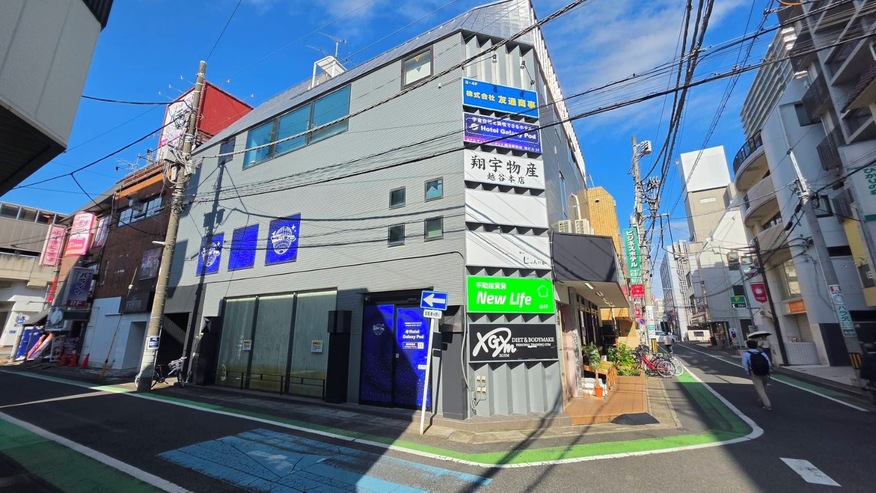 A multi-story building with signage for a hotel and a gym.