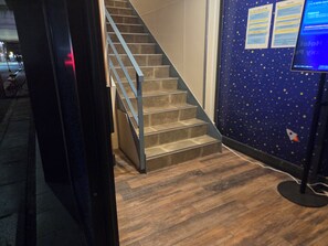 Una escalera con barandilla de metal, escalones de madera y un muro con diseño de estrellas.