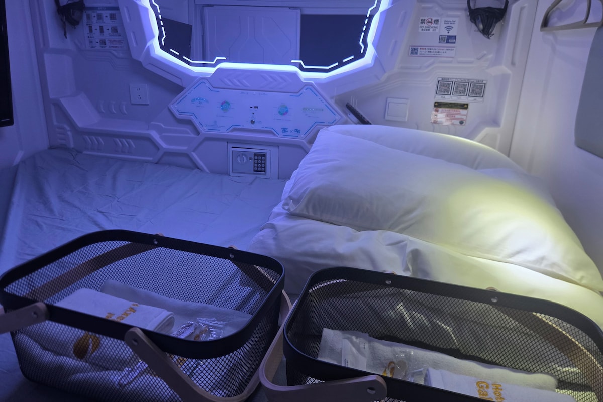 Una habitación futurista con una cama, un panel de control y una cesta de malla.