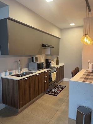 A modern kitchen with dark wood cabinets, stainless steel appliances, and a central island. - New Listing (Tijuana)