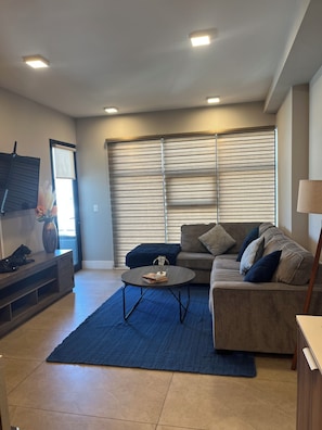A modern living room with a sofa, coffee table, and a flat-screen TV. - New Listing (Tijuana)