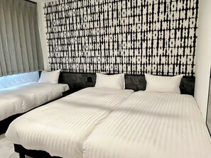 Ein Hotelzimmer mit zwei Betten, einer gemusterten Wand und einem Fenster mit Jalousien.