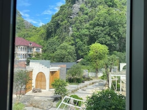 A view of a mountainous landscape with a building featuring a large wooden door and a stone wall. - Tam Coc Harmony Homestay (Nam Hoa Lư)