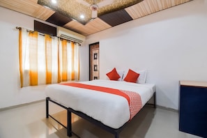 Ein Hotelzimmer mit einem Bett, Vorhängen, einer Klimaanlage und einem Deckenventilator.